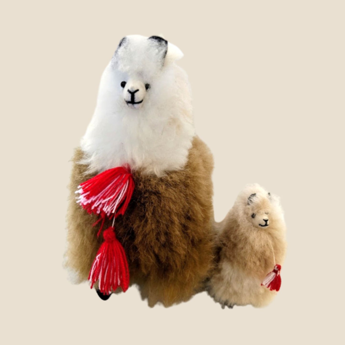 Plush toy alpaca with a smaller plush toy on a beige background