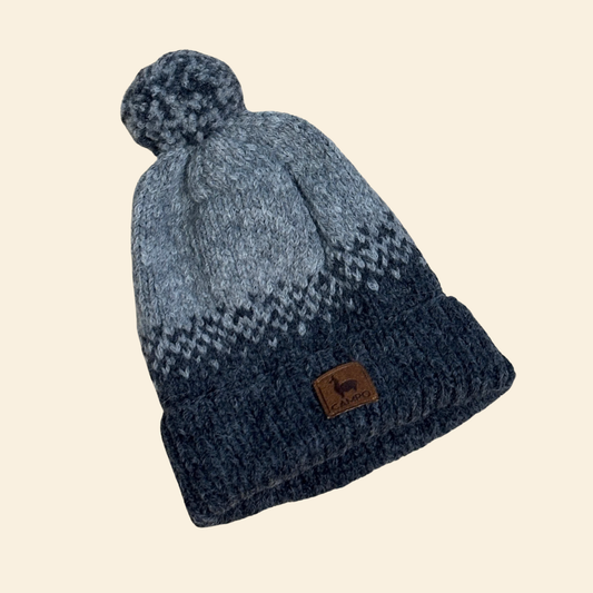 Knitted beanie with a pom-pom on a beige background