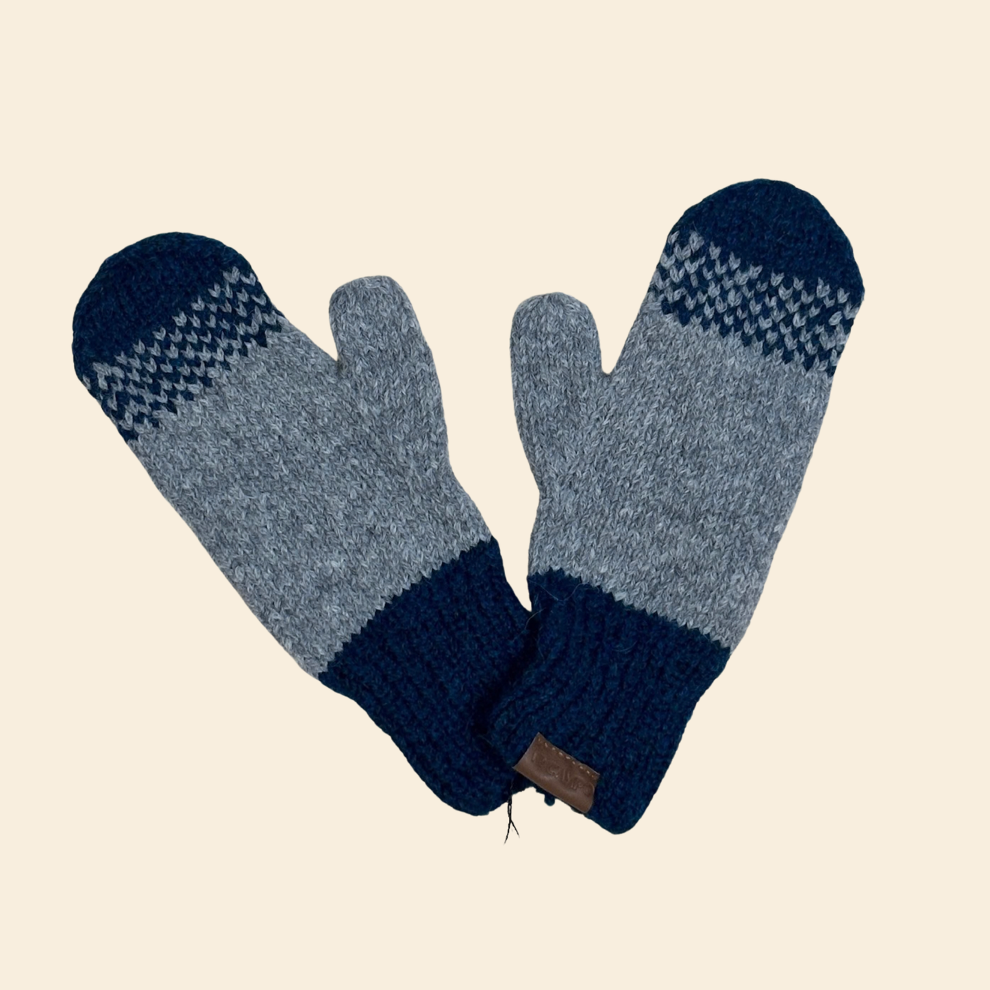 Pair of blue and gray knit mittens on a beige background