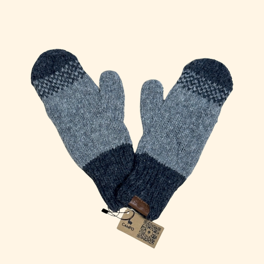 Pair of blue mittens with a brand tag on a beige background