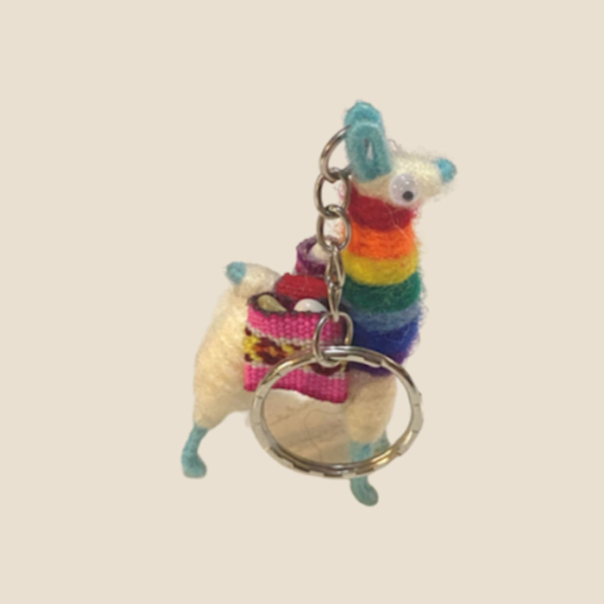 Colorful alpaca-shaped keychain with a heart charm on a beige background