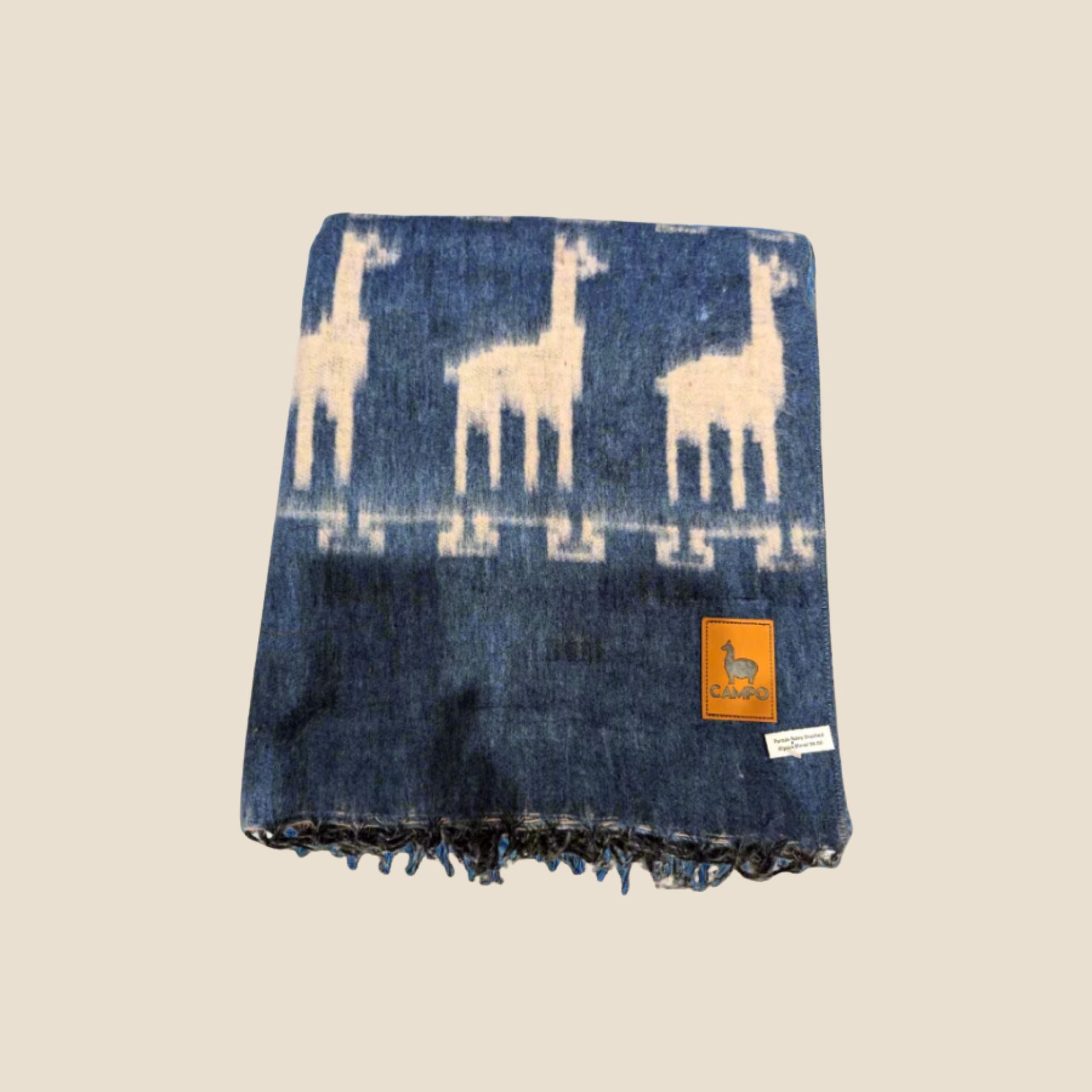 Dark Blue blanket with llama pattern and brand tag on a beige background