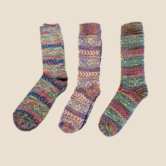 A set of three multicolored alpaca fiber socks with geometric patterns.
