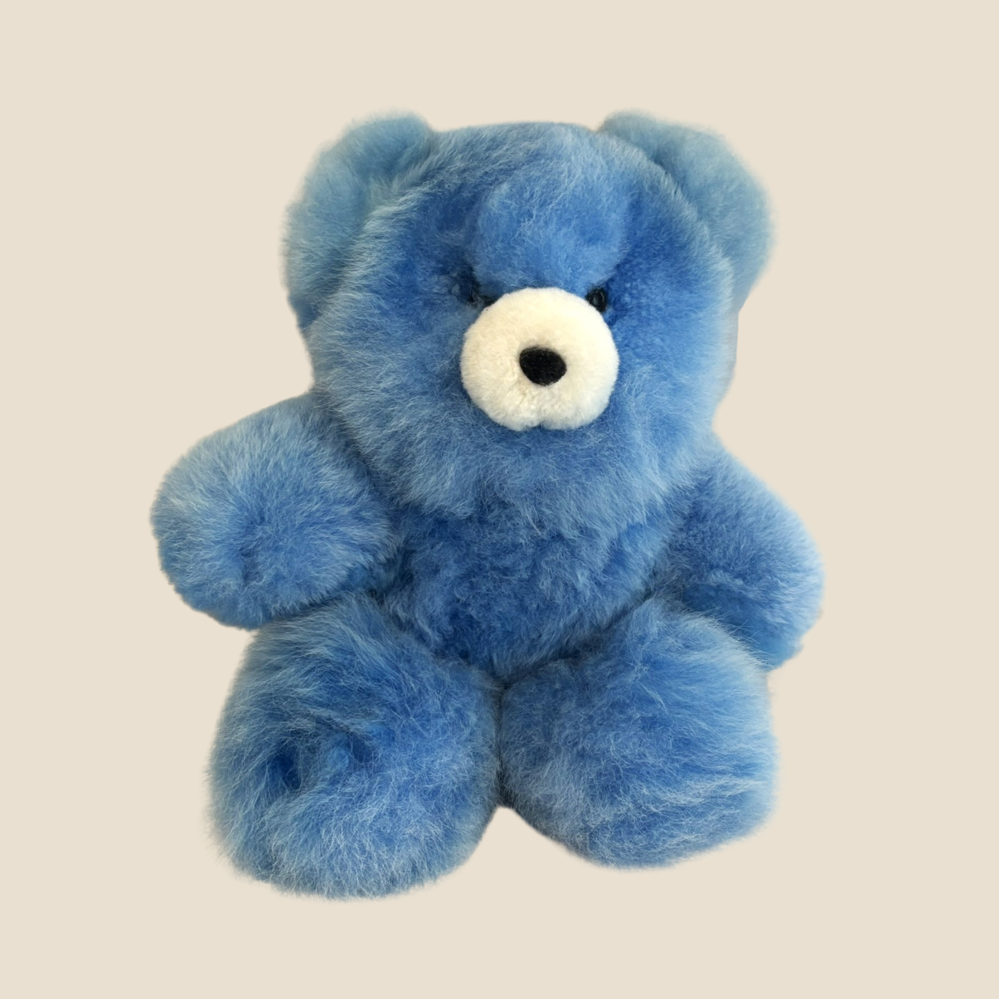 Blue teddy bear with a white nose on a beige background