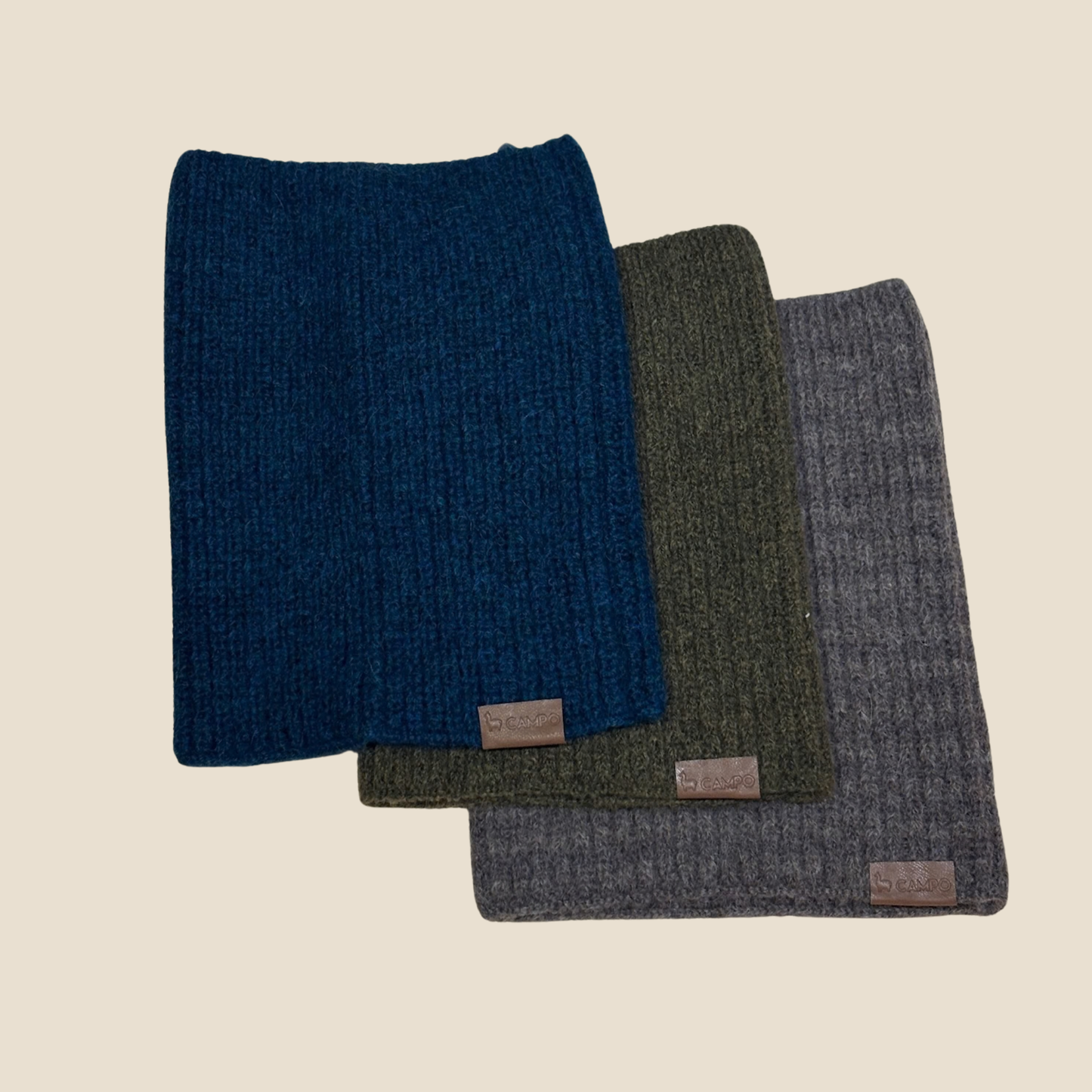 Three folded fabric swatches in blue, green, and gray on a beige background