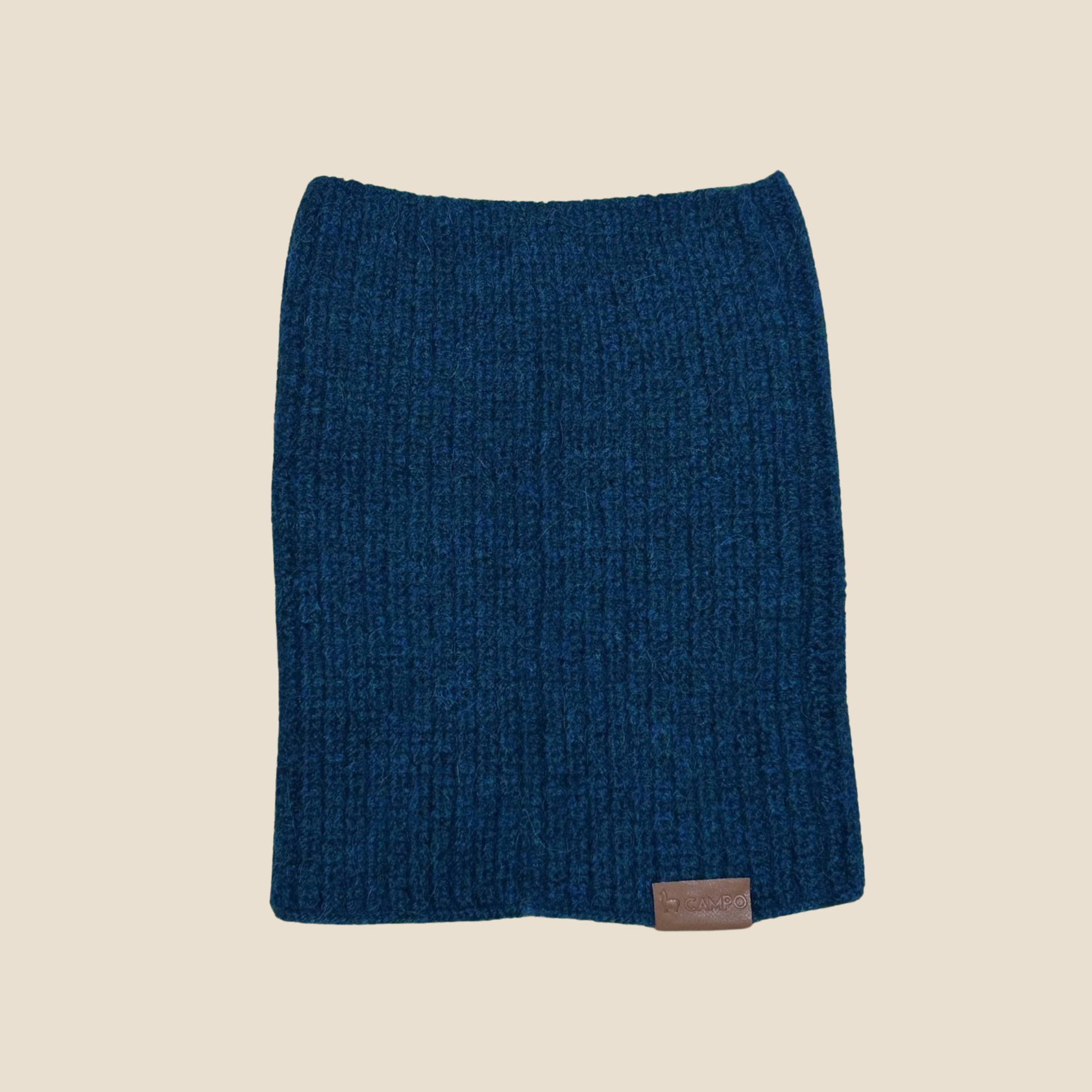 Blue knitted scarf with a brand label on a beige background