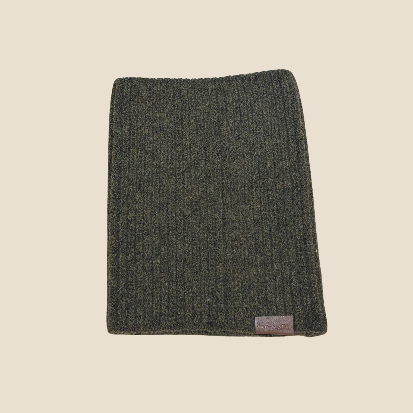 Dark green knitted scarf with a brand label on a beige background