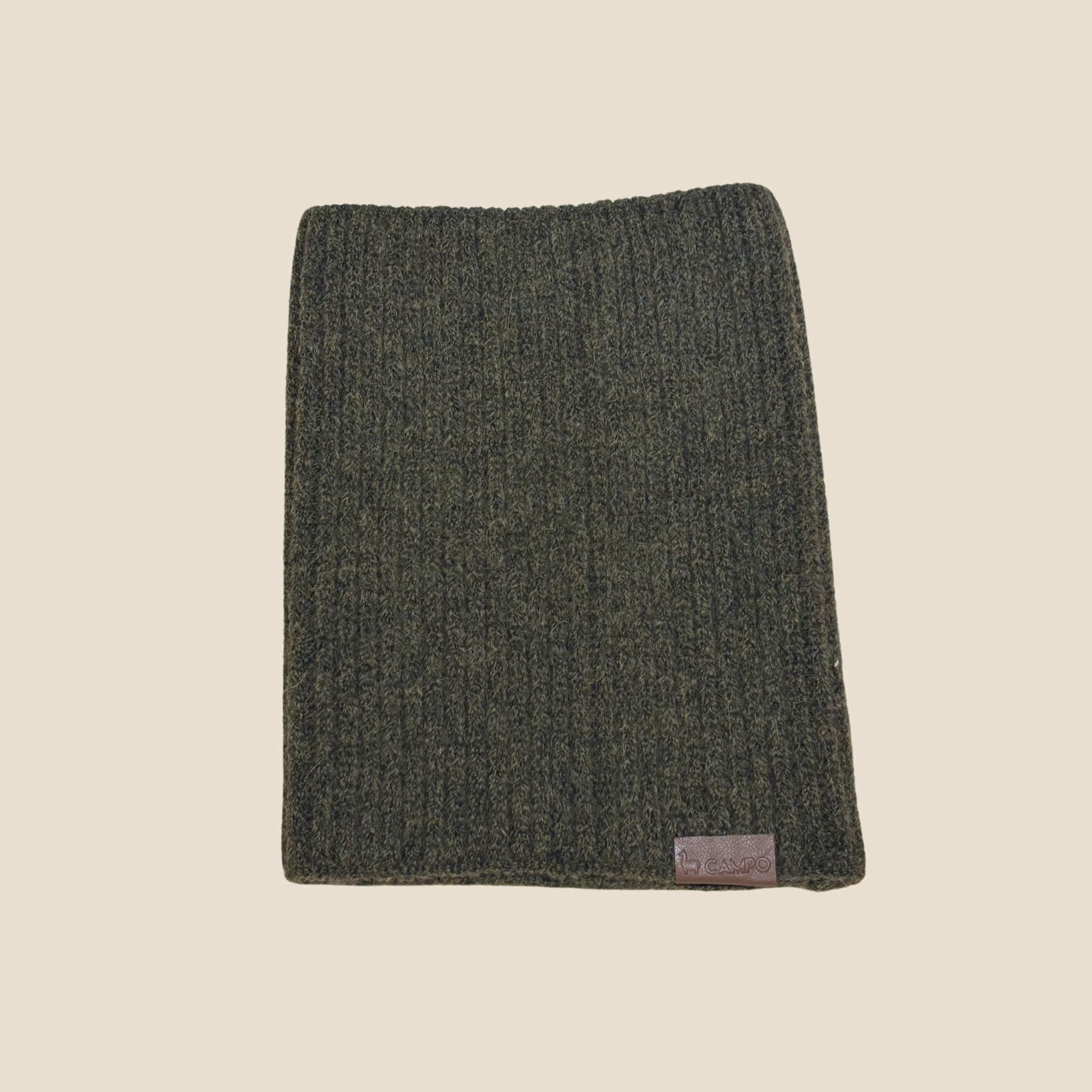 Dark green knitted scarf with a brand label on a beige background