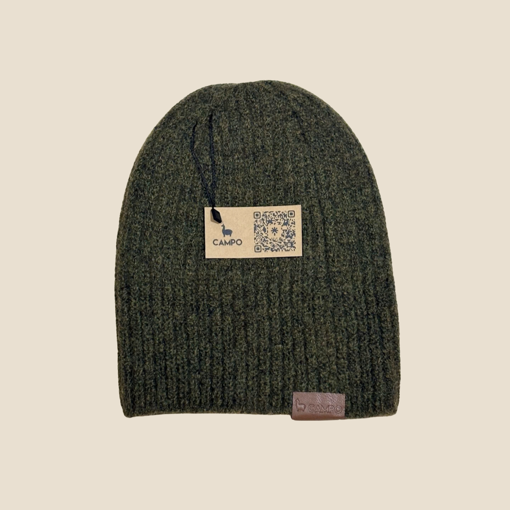 Green knit beanie with a brand label on a beige background
