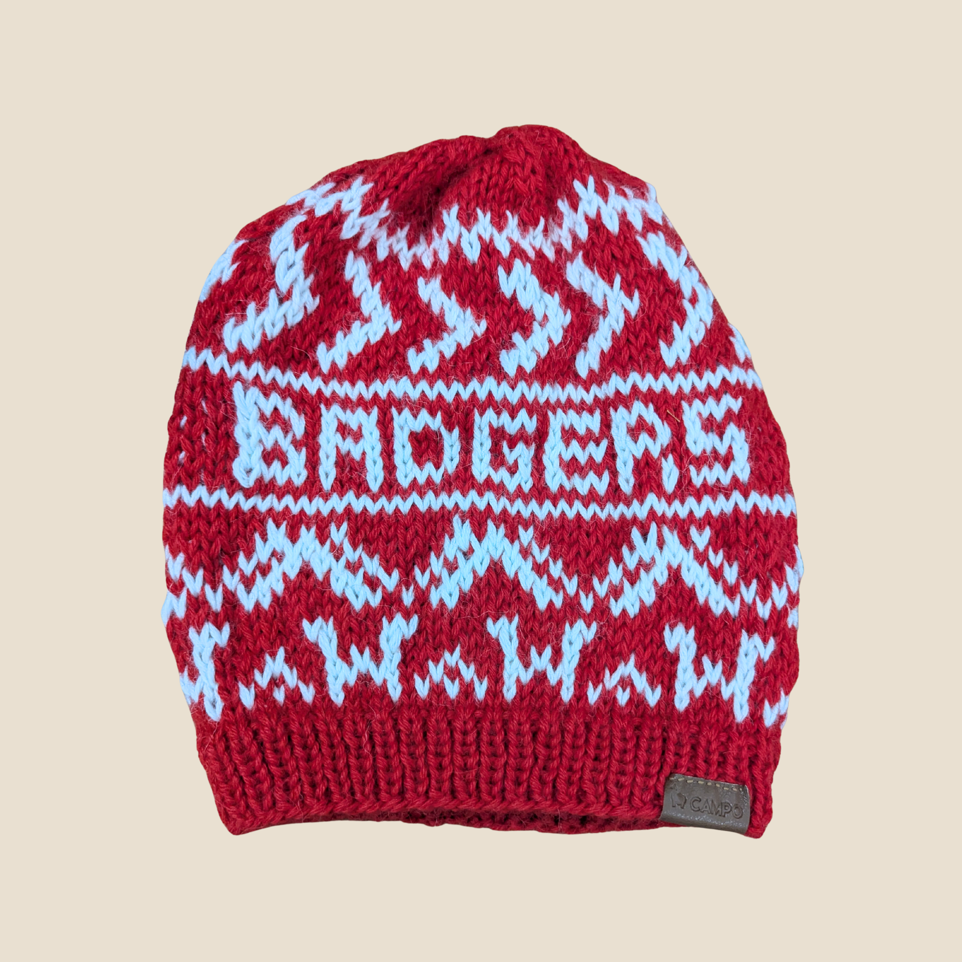 Red knit beanie with white and blue pattern on a beige background