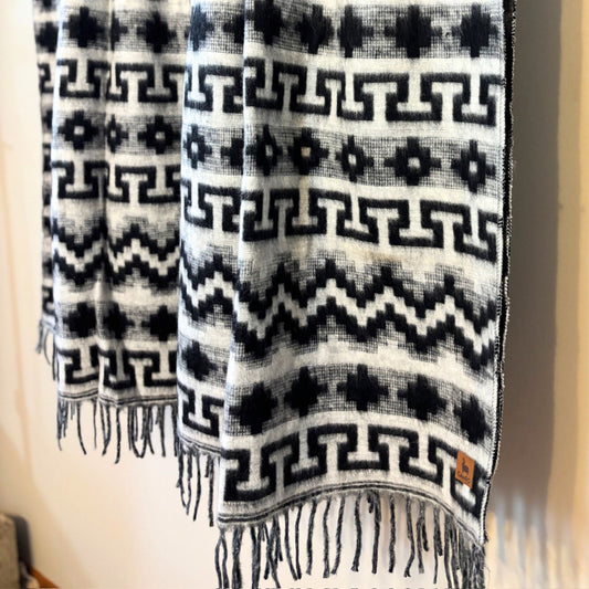 Black and white patterned scarf with fringes on a neutral background