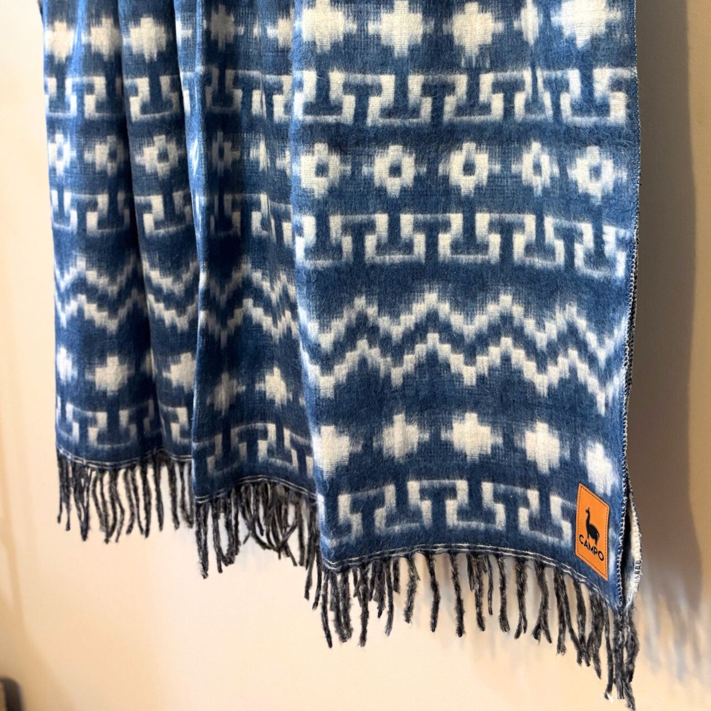 Blue and white patterned scarf with fringes on a neutral background