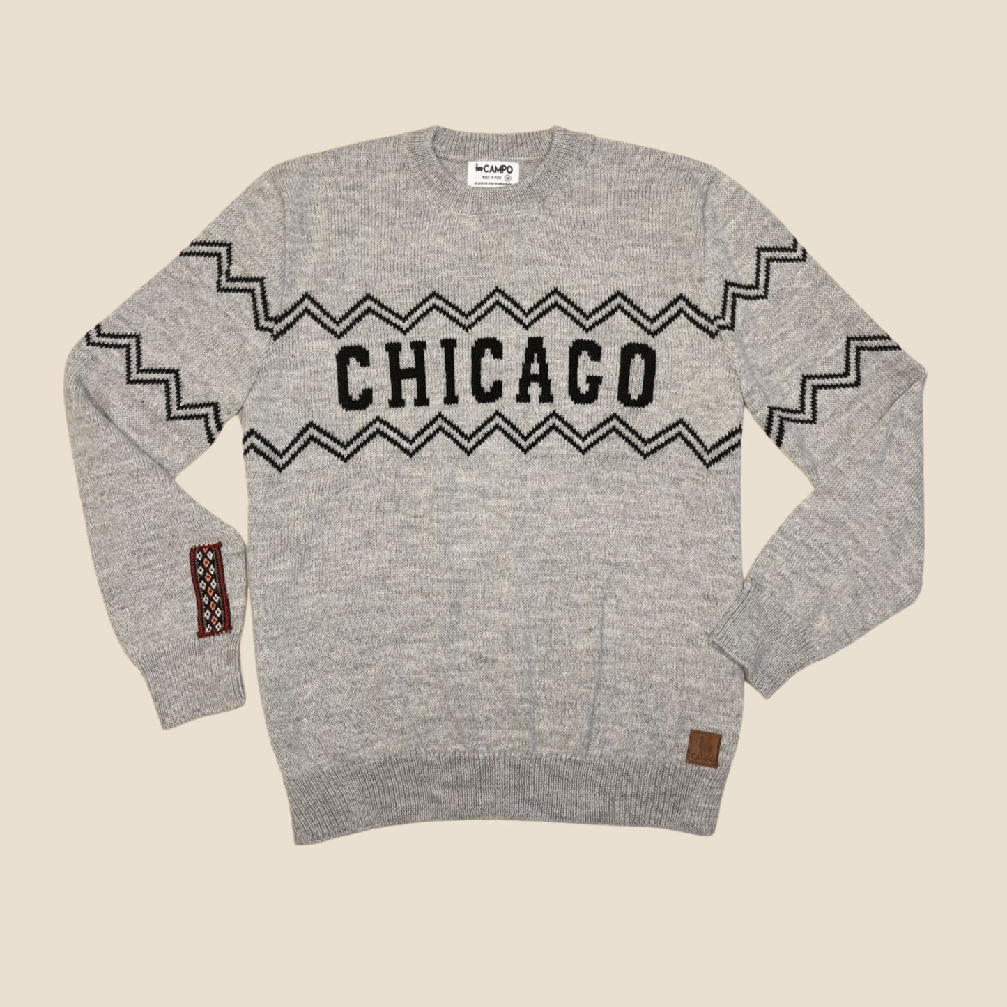 Gray sweater with 'Chicago' text and zigzag pattern on a beige background