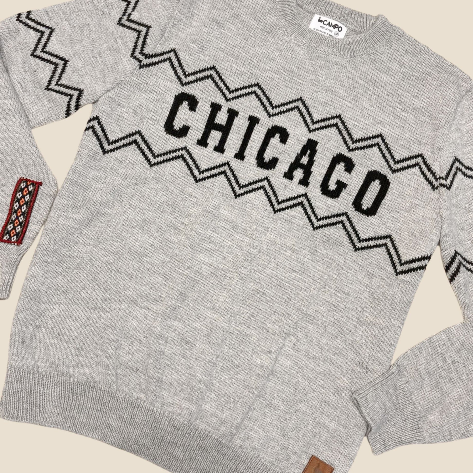 Gray sweater with 'Chicago' text and geometric pattern on a beige background