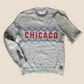 Gray sweater with 'Chicago' design on a wooden surface