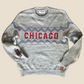 Gray sweater with 'Chicago' design on a wooden surface