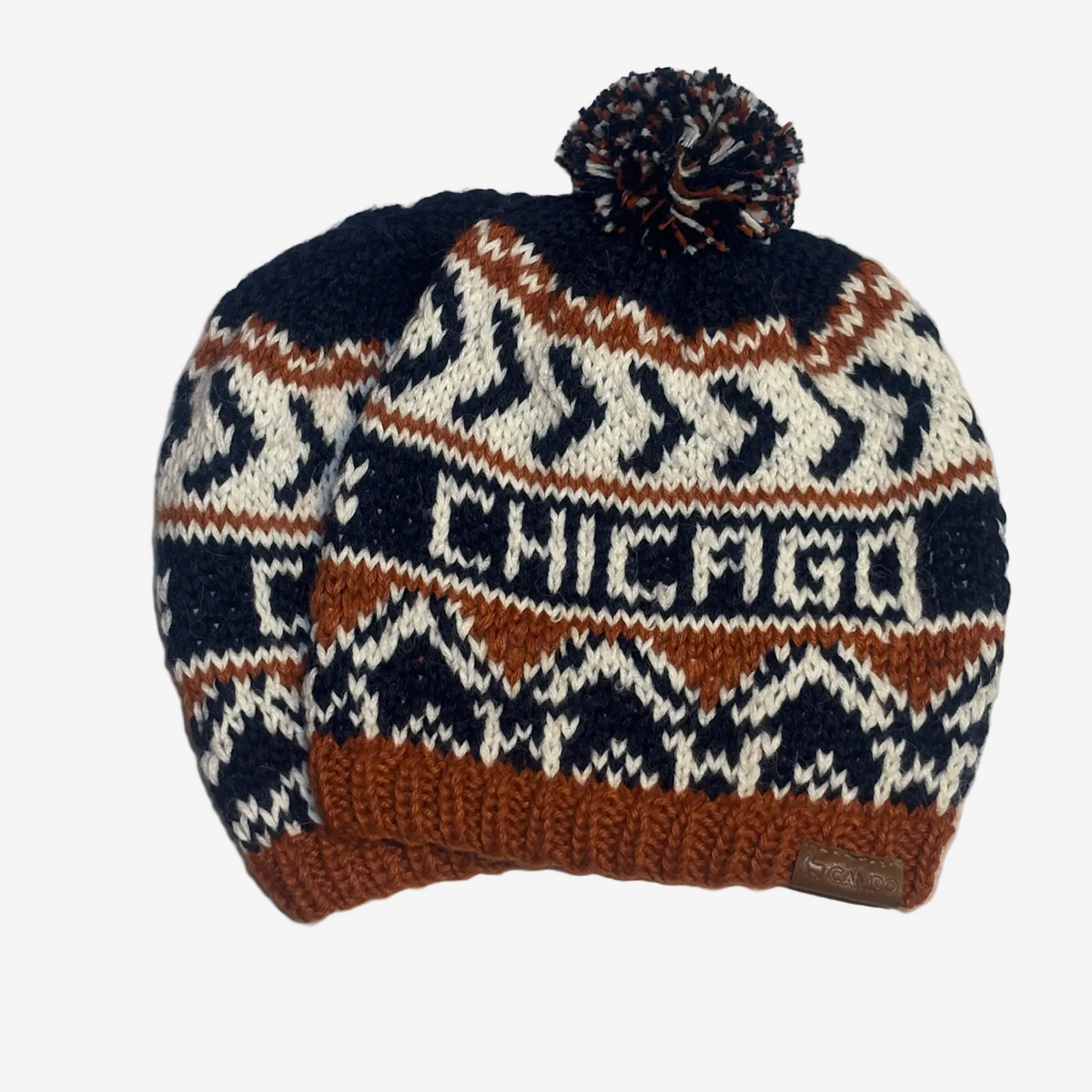 A hand-knit winter beanie hat featuring a dark navy blue top, a brown and cream geometric pattern, the word 'CHICAGO' knitted across the front, and a matching brown pom-pom on top.