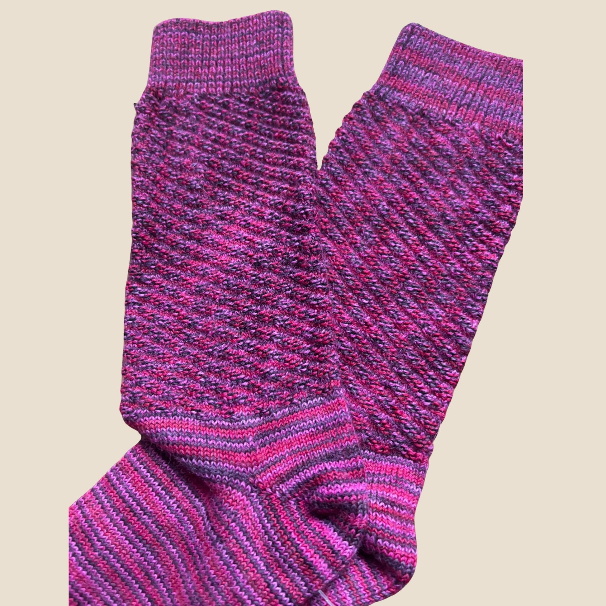 Pair of pink and purple striped socks on a beige background
