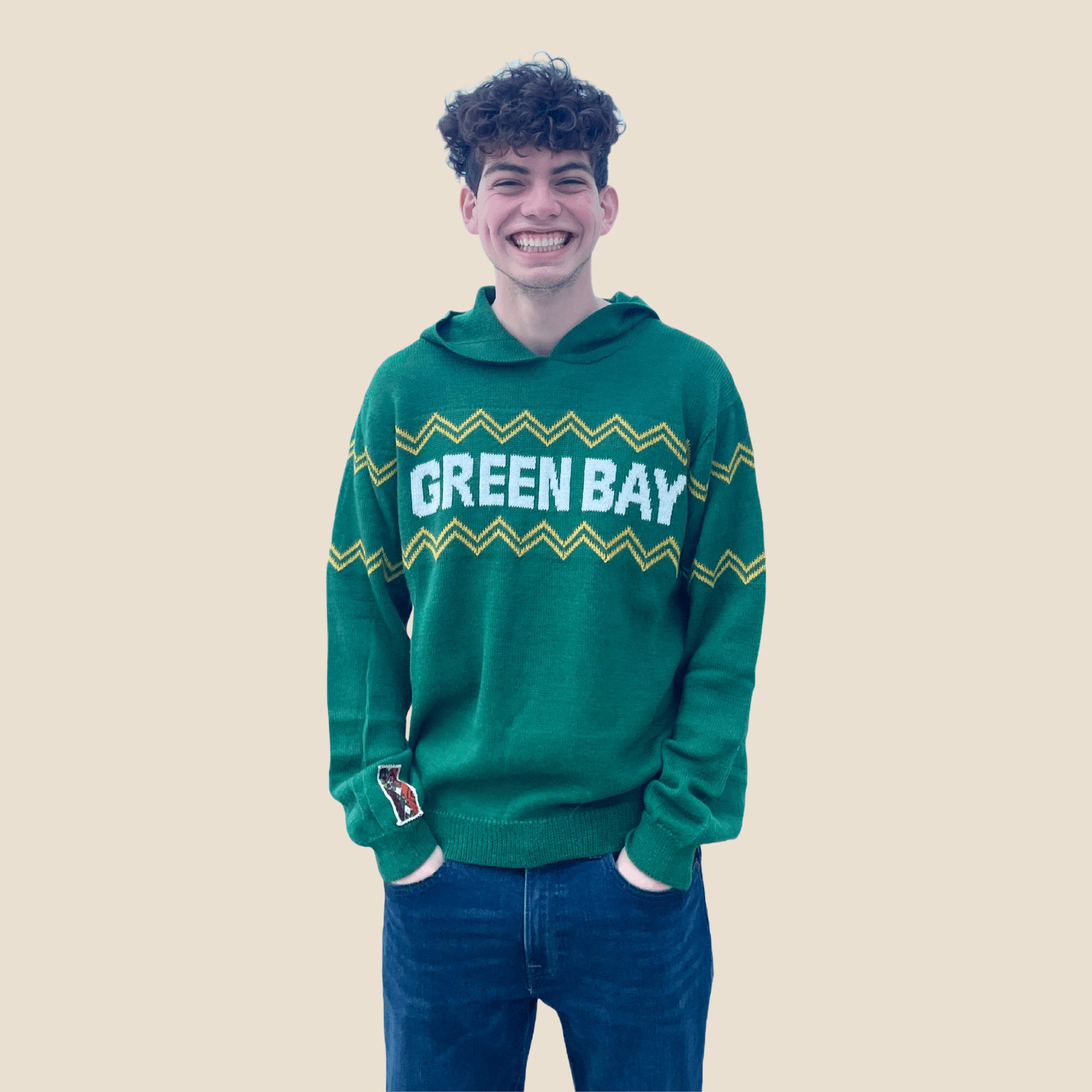 Person wearing a green 'Green Bay' hoodie on a beige background