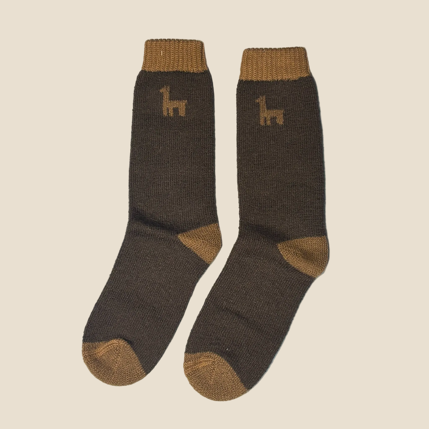 A pair of dark brown knit socks with tan accents on the cuffs, heels, and toes, featuring a small tan llama graphic on the upper calf, set against a solid light beige background.