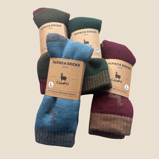 Three pairs of alpaca socks with visible labels on a beige background