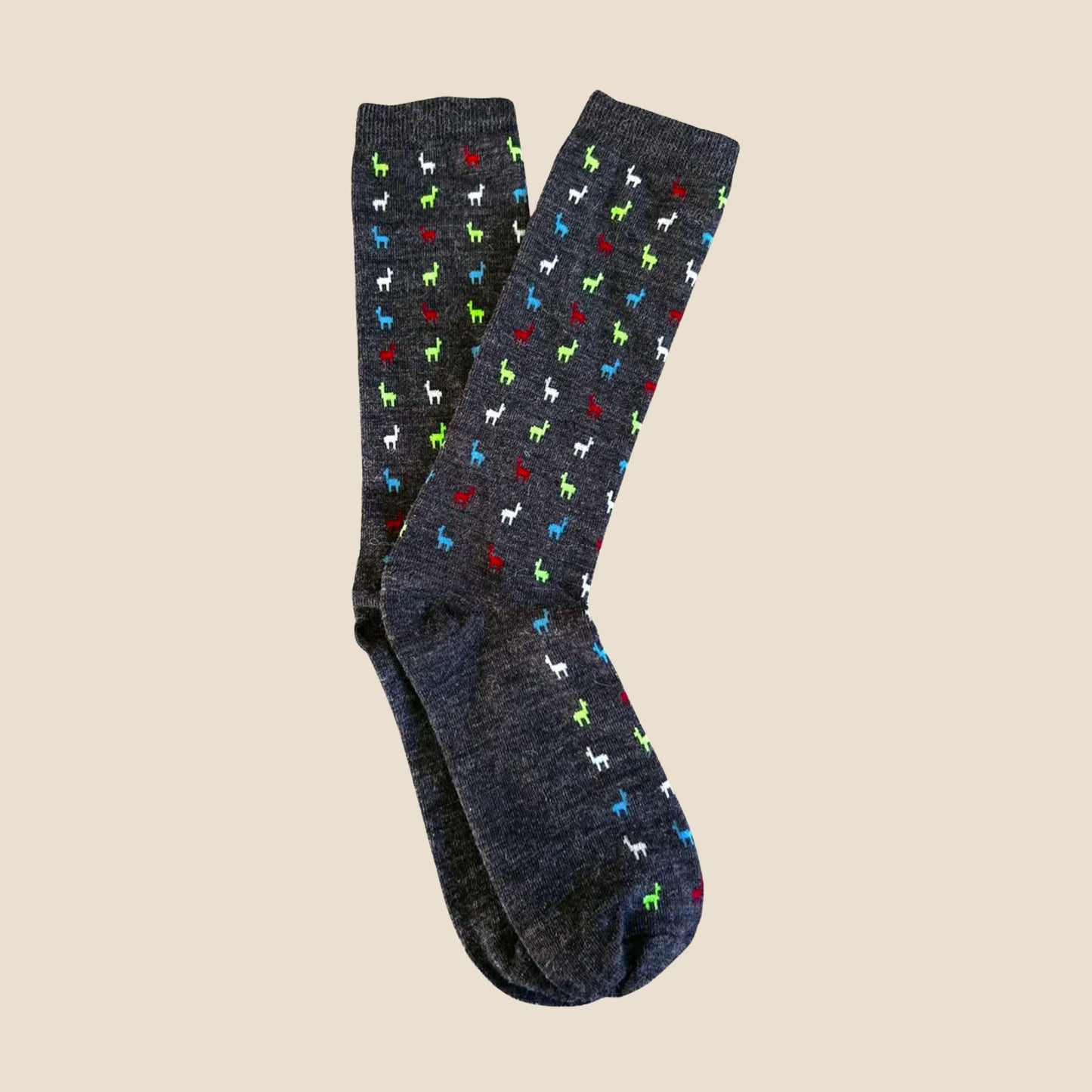 Pair of gray socks with colorful alpaca pattern on a beige background