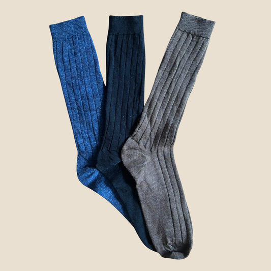 Three pairs of knee-high socks in navy, blue, and gray on a beige background