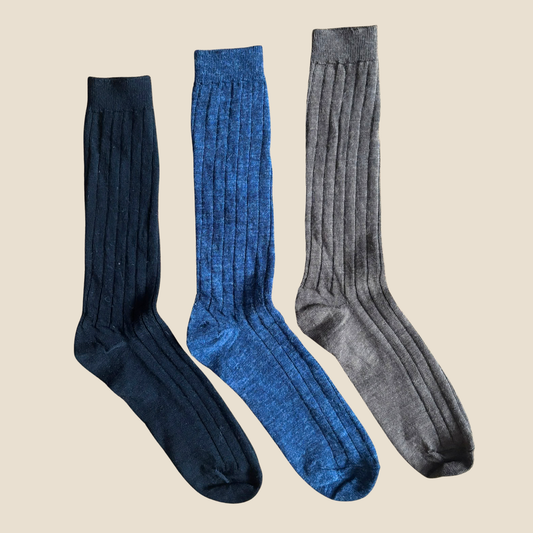 Three pairs of knee-high socks in navy, blue, and gray on a beige background