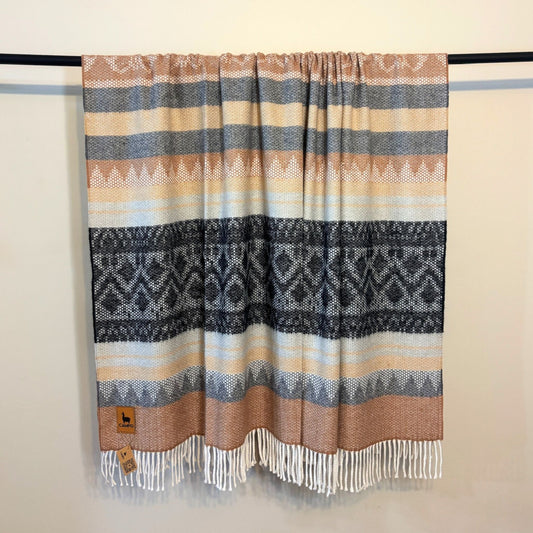 Black medley woven blanket with geometric pattern and fringes on a plain background