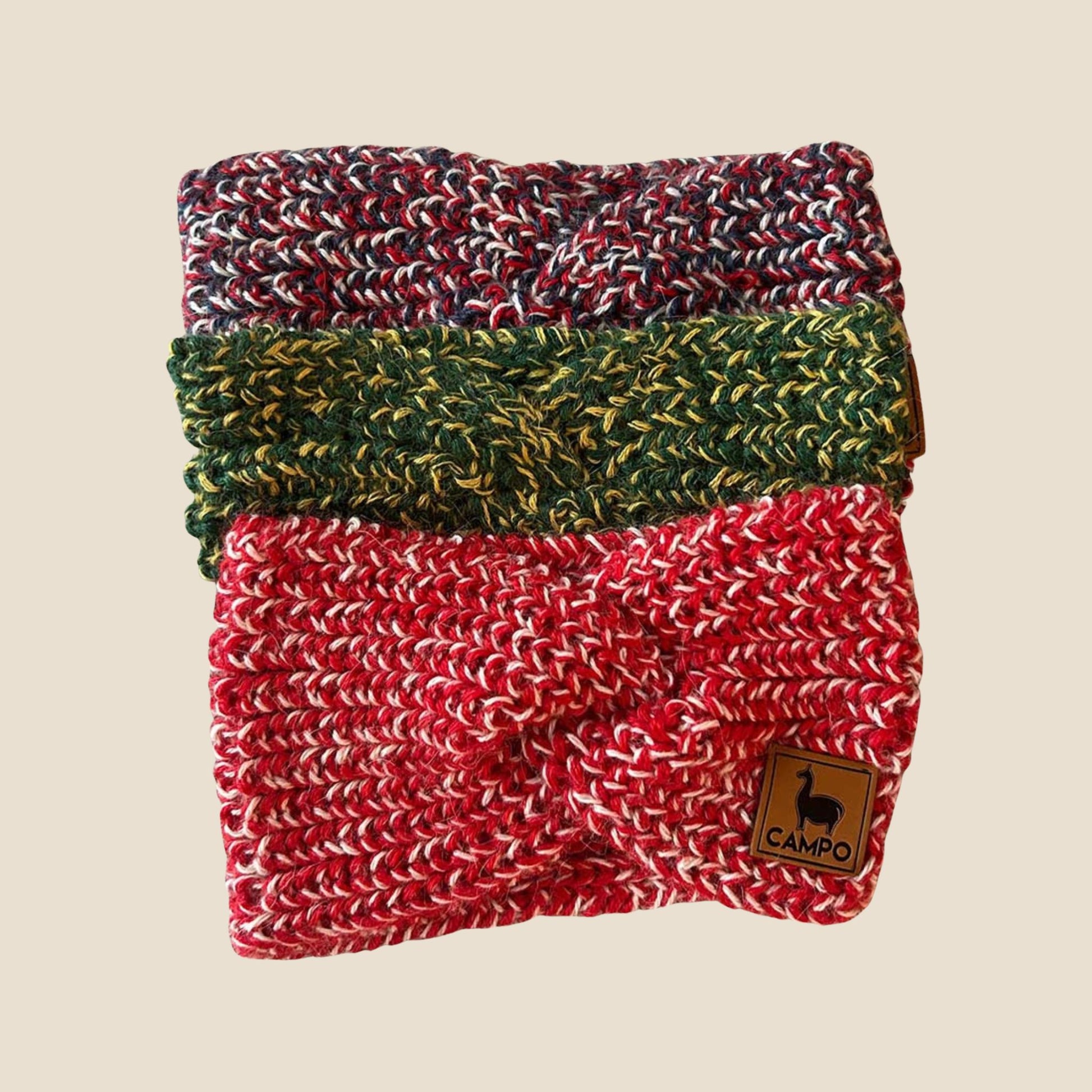 Stack of three twisted headbands in red, green, and multicolor on a beige background with 'Campo' brand label.