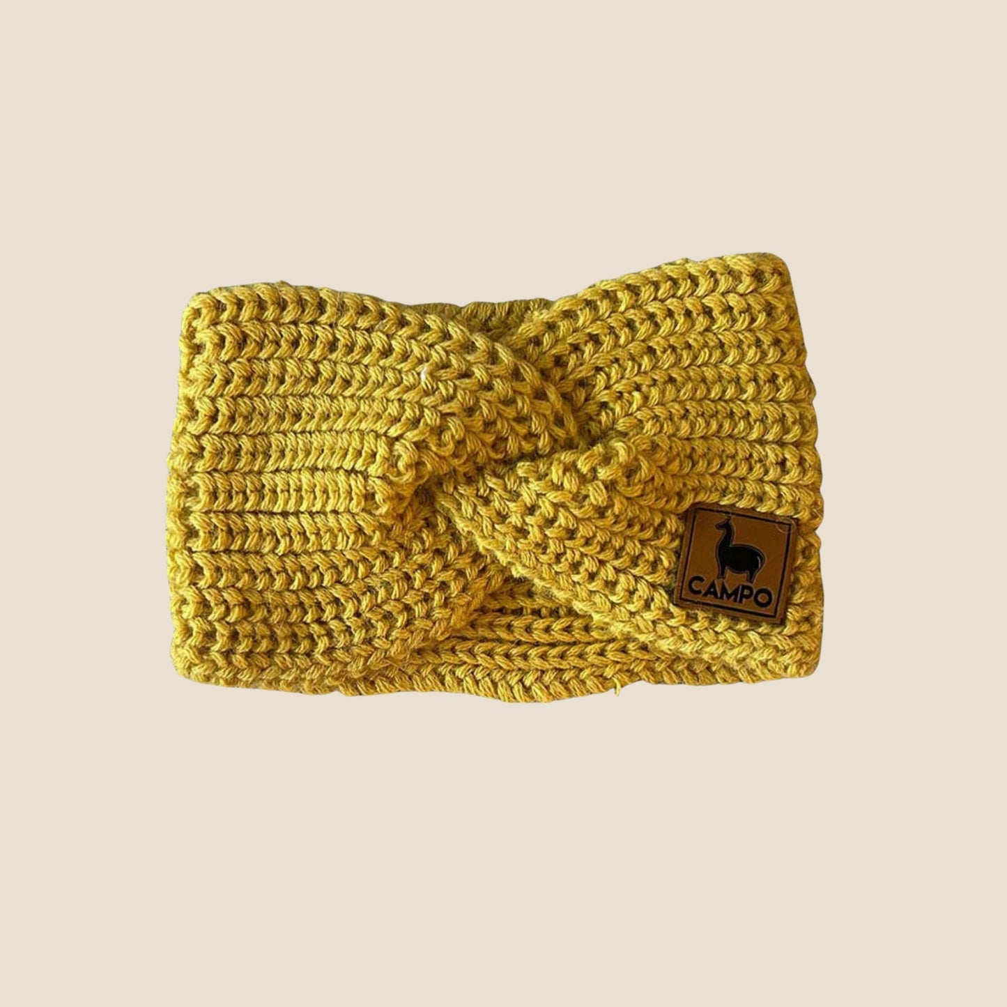 Mustard knitted headband with a brand logo on a beige background