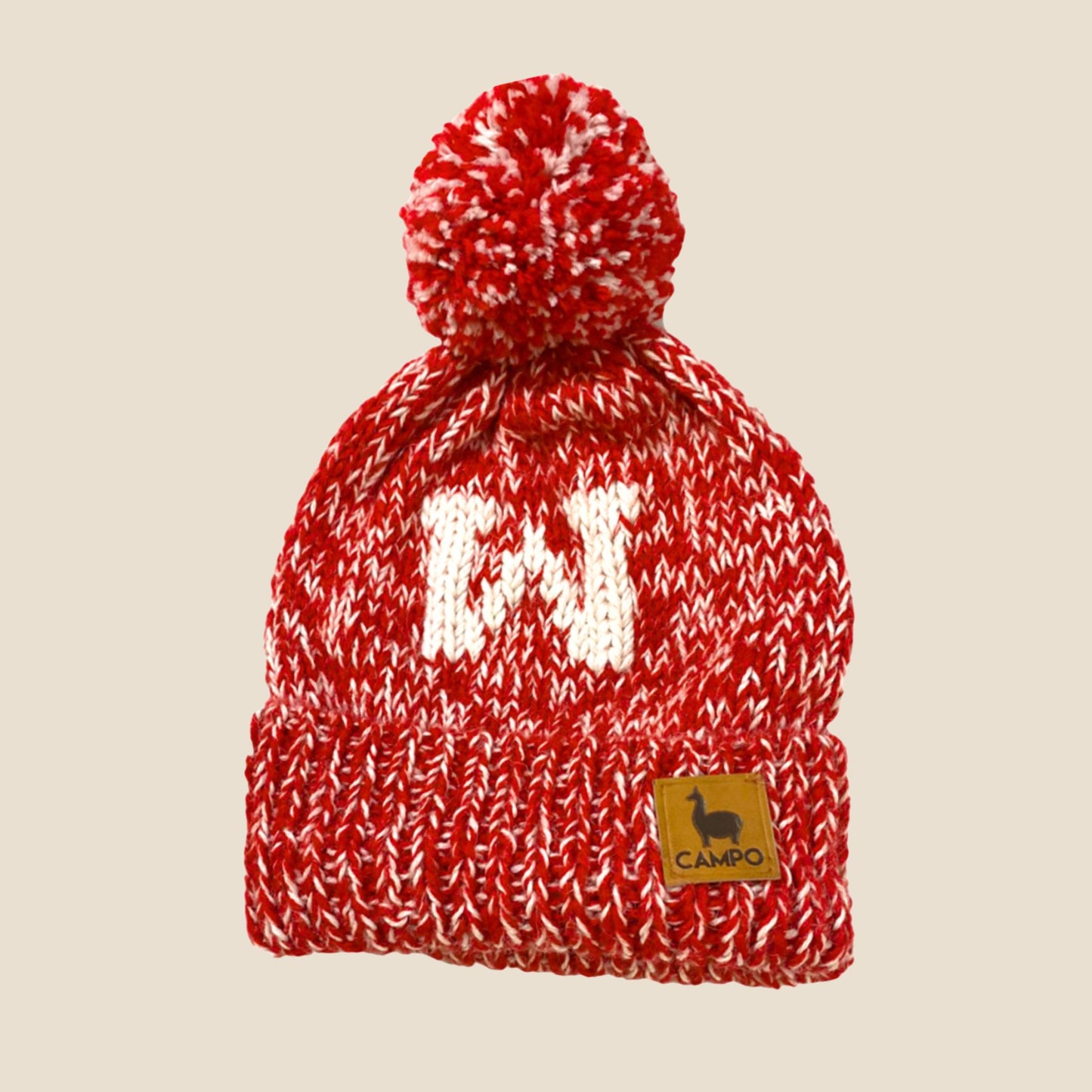 Red and white knitted beanie with pom-pom on a beige background