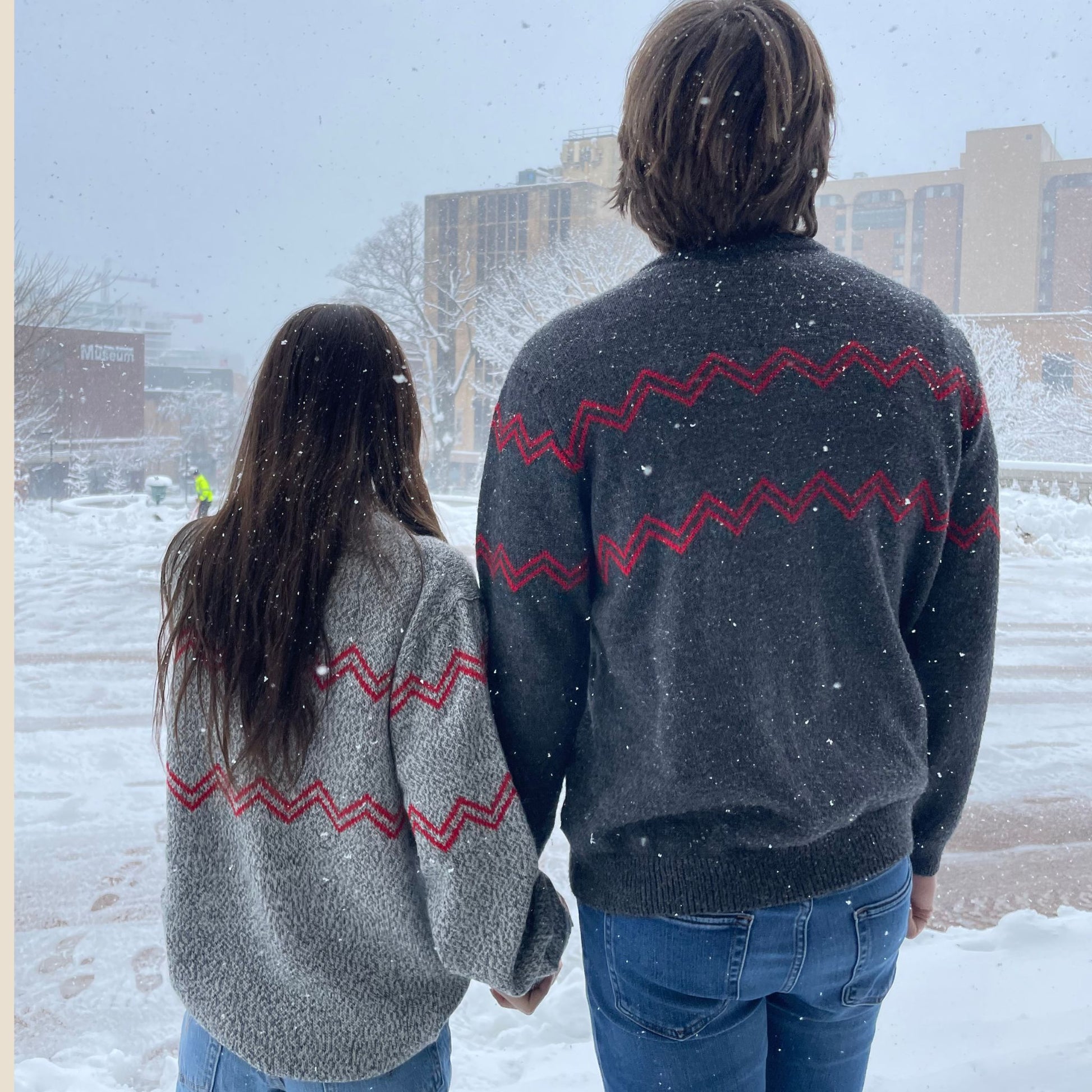 Two people wearing matching sweaters with zigzag patterns in a snowy setting.