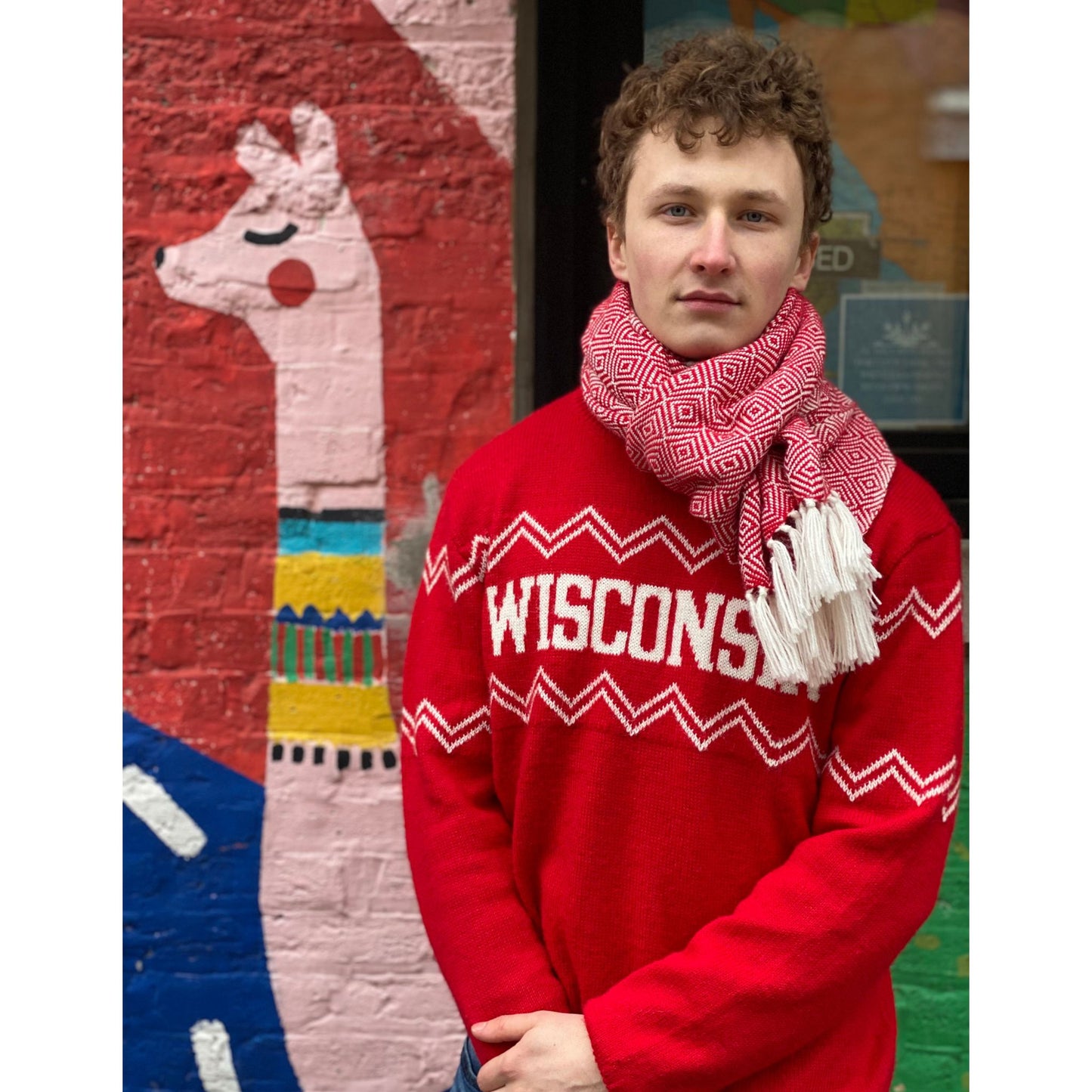Person wearing a red 'WISCONSIN' sweater with a colorful mural in the background