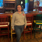 Person wearing a beige sweater with a red logo in a bar setting
